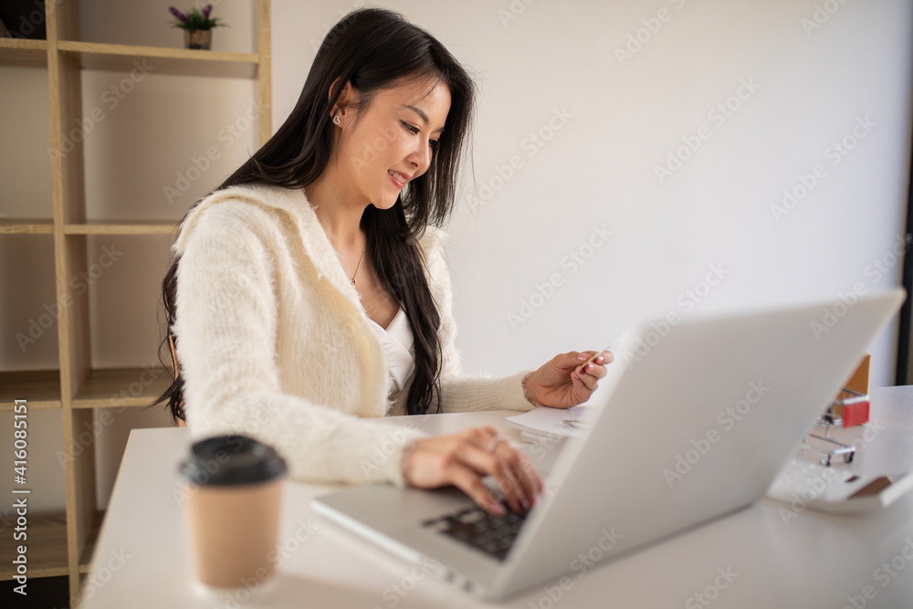 Fototapeta premium Portrait of Young woman using credit card,smartphone and laptop computer at home. Online shopping, e-commerce, internet banking, spending money, working from home concept