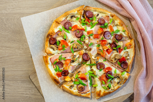 Cutted pizza on light wooden table.