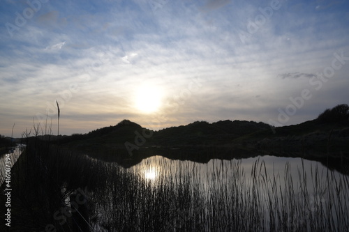 the sand dunes of ynyslas wales reflected in the flooded waters  next to the road 