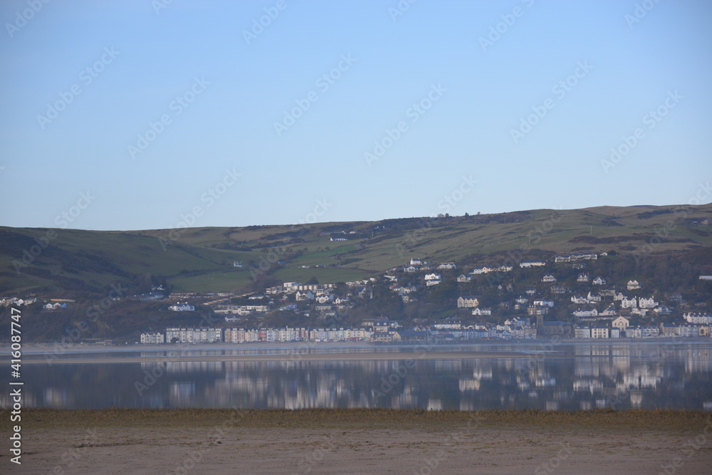 a view of aberdovey from ynyslas reflected in the estuary