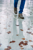 Boy teenager in boots jumps, runs through the puddles in the cold autumn