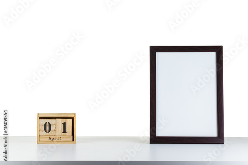 Wooden calendar 01 april with frame for photo on white table and background
