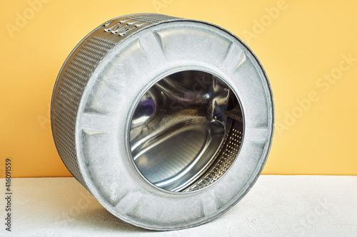 Metal drum washing machine. repairs clothes washer. Yellow background