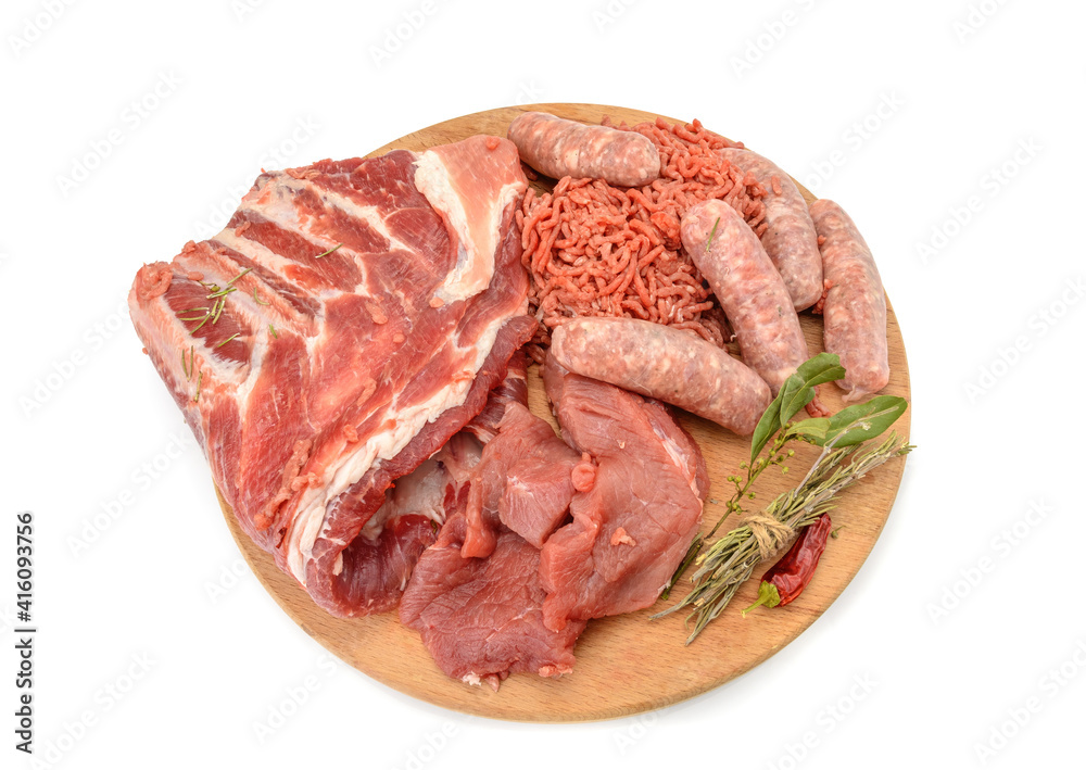 Raw meat products.Shish Kebab of pork ribs, steaks, fried sausages, minced meat, decorated with spices, on a round wooden cutting board.isolated on a white background.Flat layout.