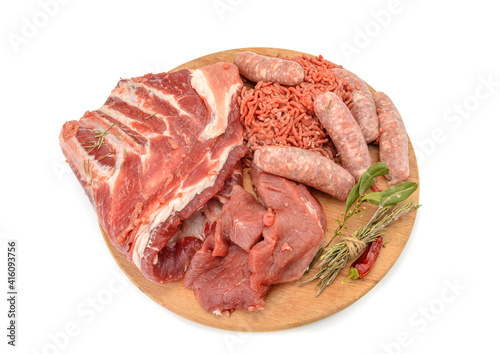 Raw meat products.Shish Kebab of pork ribs, steaks, fried sausages, minced meat, decorated with spices, on a round wooden cutting board.isolated on a white background.Flat layout.