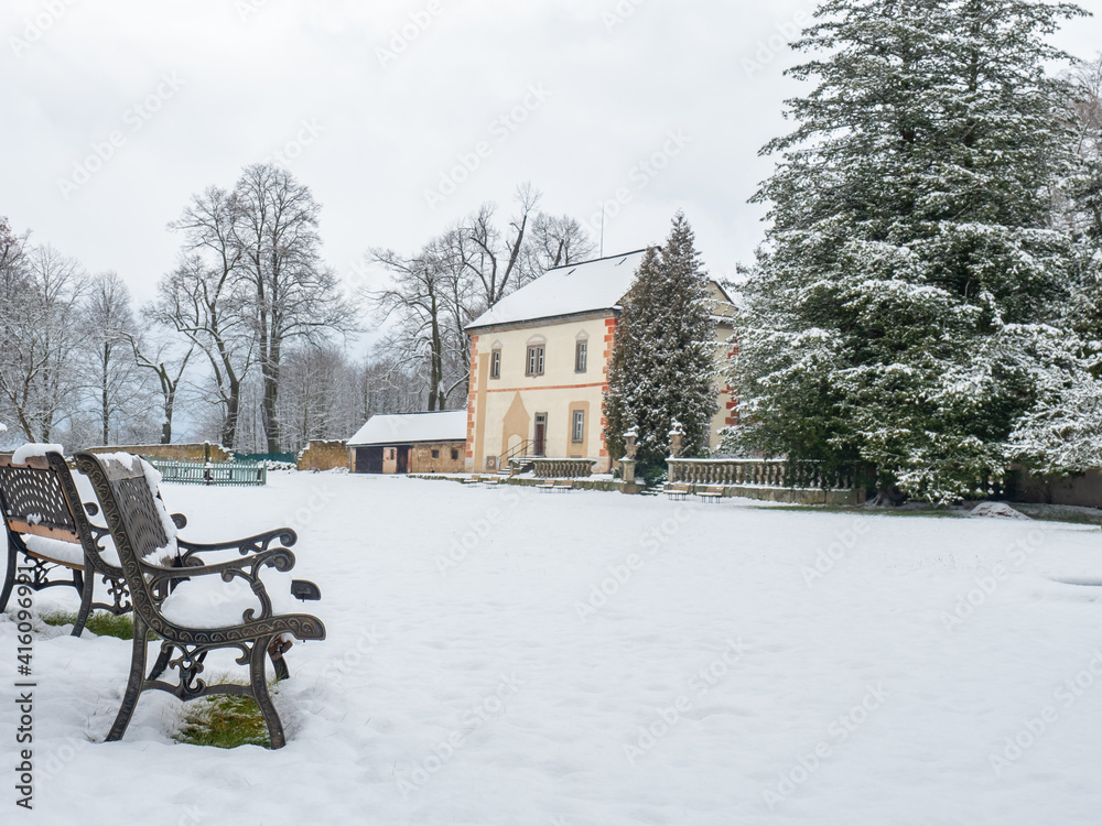 Winter alley park with a bench and historical building in snowy park Winter alley park with a bench and historical building in snowy park