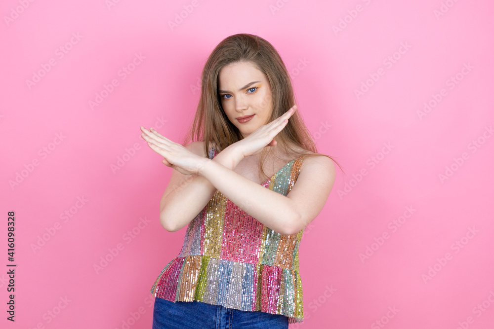 Pretty redhead woman wearing a shiny top standing over pink background Rejection expression crossing arms doing negative sign, angry face Pretty redhead woman wearing a shiny top standing over pink background Rejection expression crossing arms doing negative sign, angry face