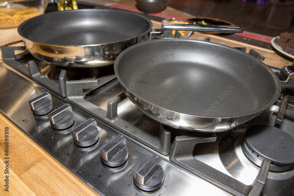 Metal pans on a chrome metal hob in a kitchen Metal pans on a chrome metal hob in a kitchen