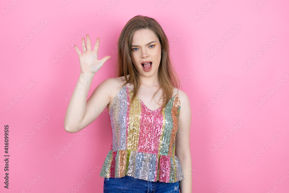 Pretty redhead woman wearing a shiny top standing over pink background showing and pointing up with fingers number five while smiling confident and happy Pretty redhead woman wearing a shiny top standing over pink background showing and pointing up with fingers number five while smiling confident and happy