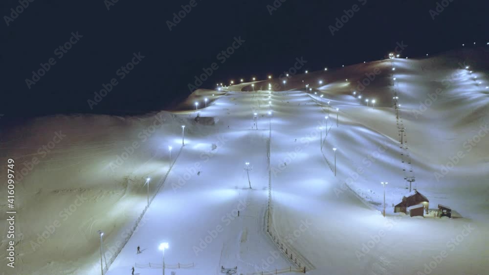 Enchanting Bláfjöll Ski resort lid up by floodlights, aerial dolly forward.