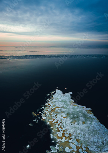 Aerial view on frozen seawater at a beautiful sunset against a blue sky, winter by the sea © Aleksandrs Muiznieks