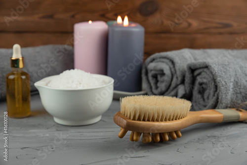 Herbal therapy, traditional medicine and homeopathy concept. Towel with salt, herbs, massage brush, candles and bottle natural organic oil essence serum. Set for spa, massage and aromatherapy 