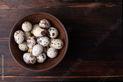 Canvas Print Fresh quail eggs in a bowl on a dark wooden background, rustic style