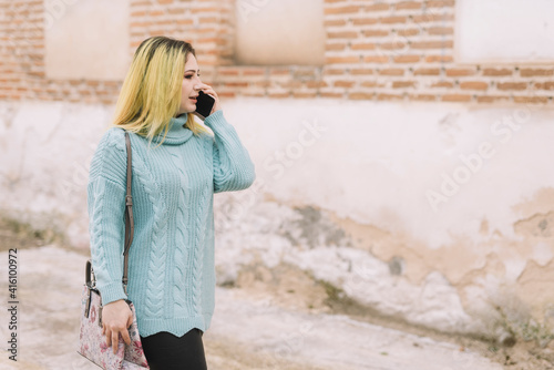 Dark root blonde female talking on smartphone with copy space © Alvaro