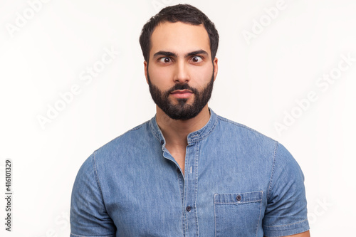 Funny amused man with beard in blue shirt crossing his eyes looking crazy and stupid, fooling around, having fun, vision problems. Indoor studio shot isolated on white background photo