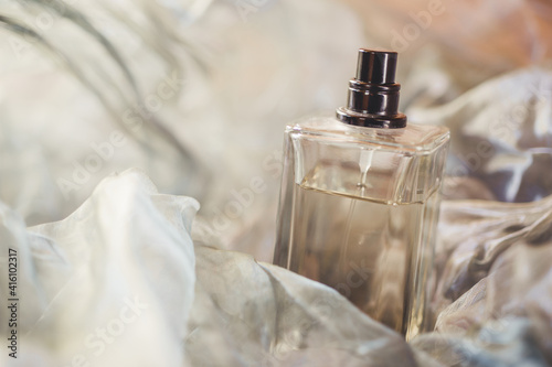 Bottle with perfume on an airy fabric close-up. photo