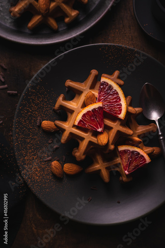 Belgian waffles with orange on a plate, flat lay