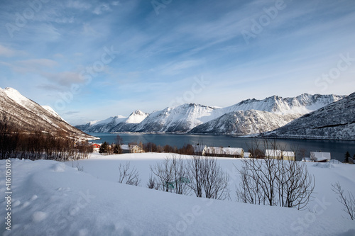 Scenery of snow mountain range and norwegian village on coastline in winter at Senja Island