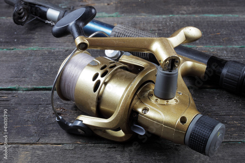 Fishing spinning rod with a gold reel on a dark background, close-up.