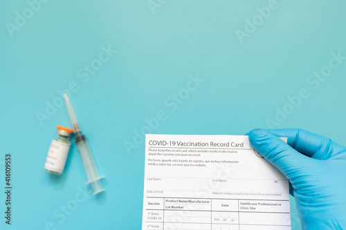 Doctor is holding a vaccination record card and corona virus vaccine vials. Passport of immunity to the coronavirus in the hands of a male doctor. Health passport.