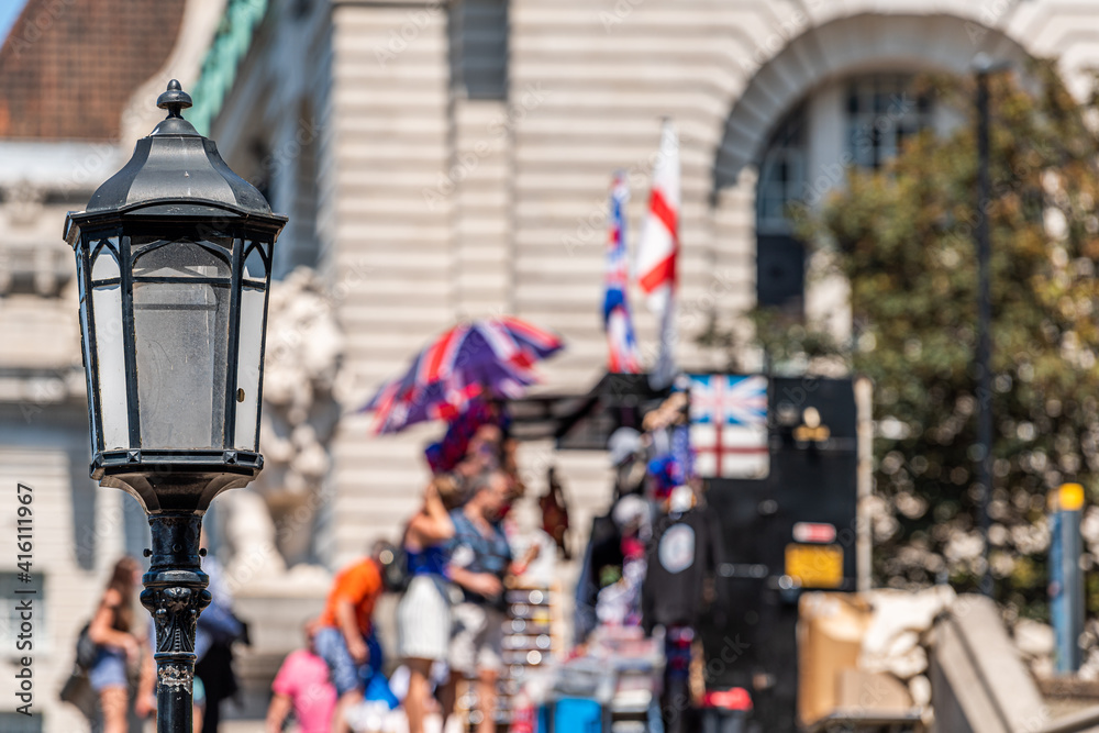People walking on street with union jack flag umbrella and closeup of lantern in United Kingdom bokeh background