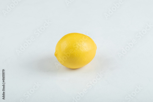 A whole fresh lemon on white surface