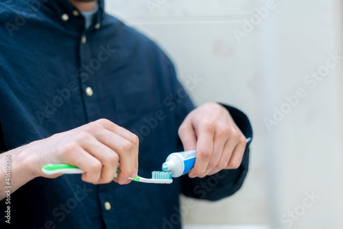 person squeeze toothpaste on a toothbrush in bathroom