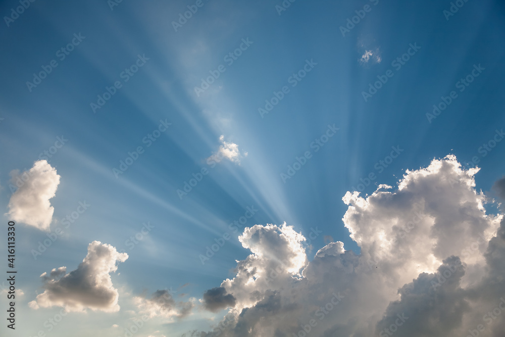 A sky with white clouds and beautiful sunbeams passing through the clouds. The magical beauty of the sky with the sun and clouds