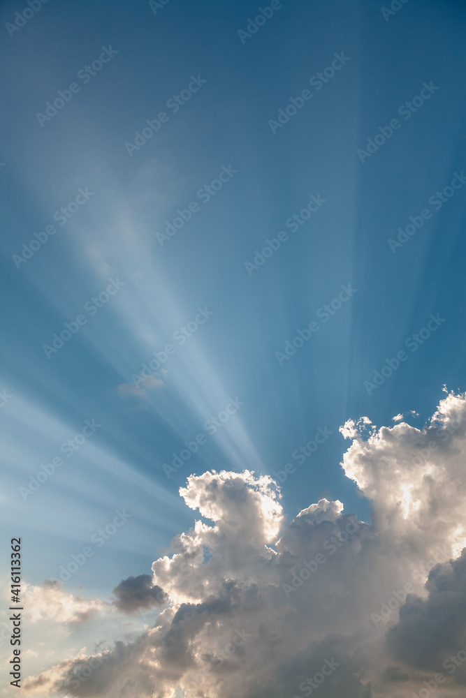 A sky with white clouds and beautiful sunbeams passing through the clouds. The magical beauty of the sky with the sun and clouds