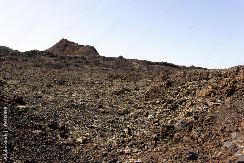 Black rocks with volcano on top at Timanfaya National Park. Volcanic natural landscape in Lanzarote island. Tourist attraction, travel destination concepts