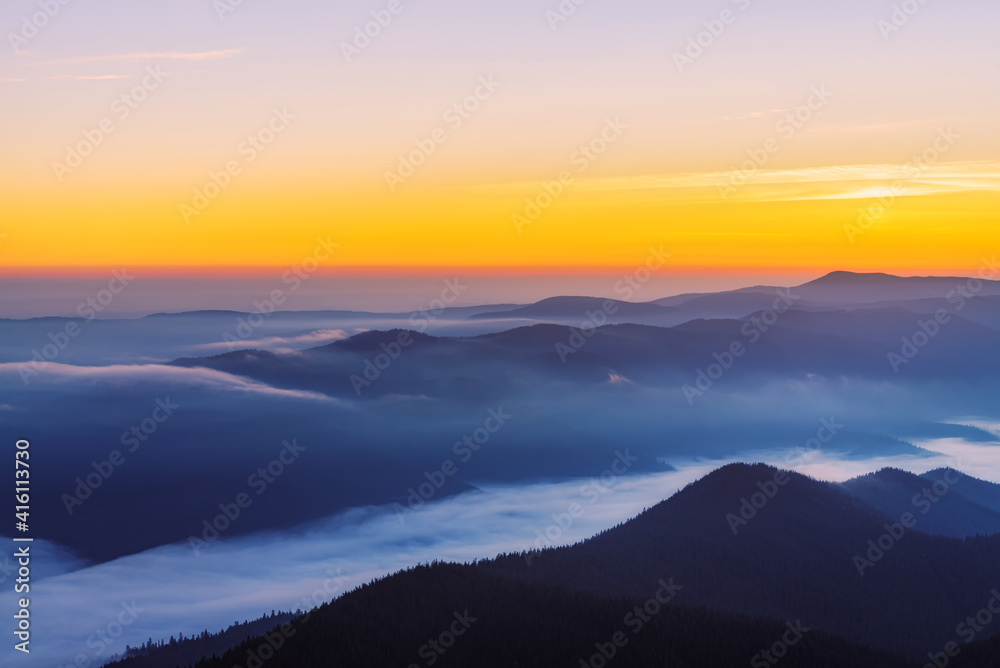 Colorful mountain landscape with thick fog in the valley at sunrise.