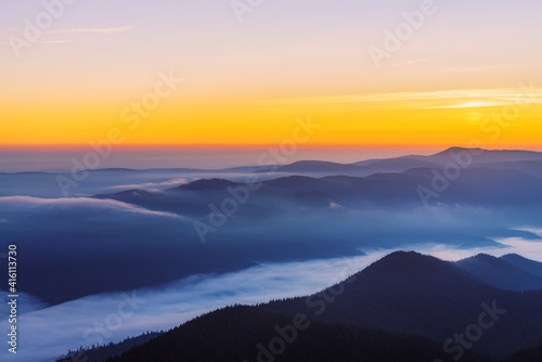 Colorful mountain landscape with thick fog in the valley at sunrise.