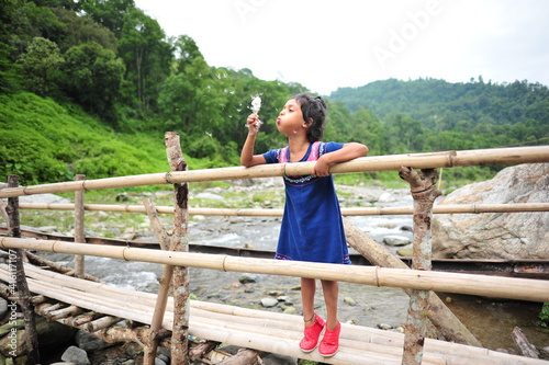 little girl in a valley blowing dandelion, happy , carefree 