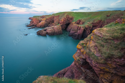 Coastal landscape of the red sandstone Seaton Cliffs during sunset or sunrise at Arbroath east coast of Angus, Scotland.