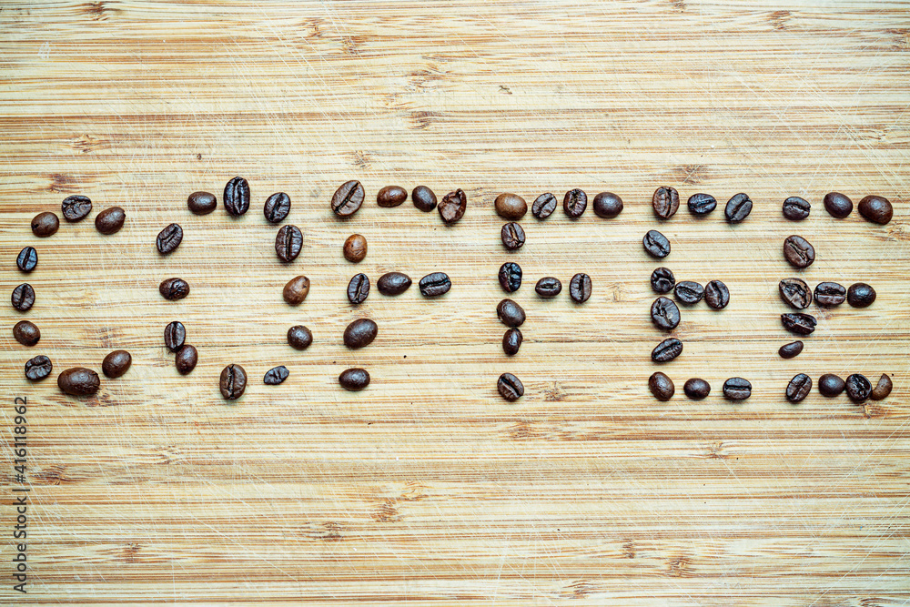 Ziarna kawy wysypane na drewniana deskę. Ziarna te tworzą napis COFFEE