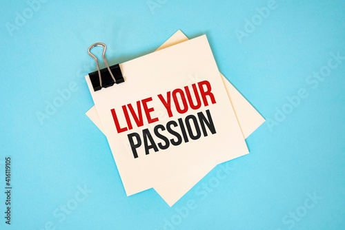 Text LIVE YOUR PASSION on sticky notes with copy space and paper clip isolated on red background.Finance and economics concept.