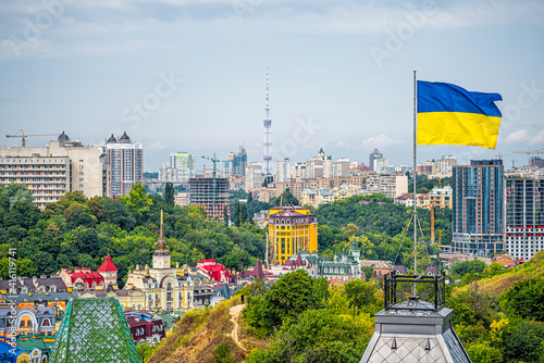 Kyiv, Ukraine cityscape of Kiev and Ukrainian flag waving in the wind during summer in Podil district and colorful new buildings photo
