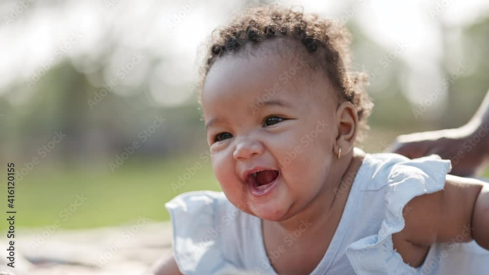 Smiling African American baby happy on mat in garden nature morning with family on vacation. Baby health care. Child development. Universal Children's Day Smiling African American baby happy on mat in garden nature morning with family on vacation. Baby health care. Child development. Universal Children's Day