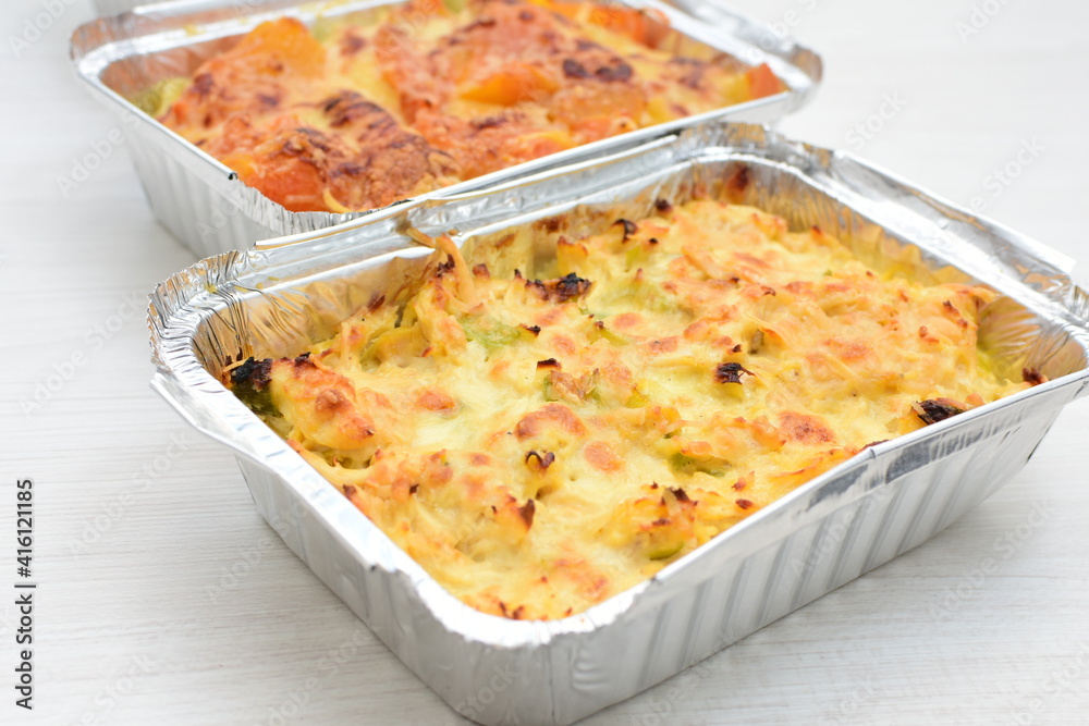 Baked chicken and mushroom cannelloni, bathed in cream in cheese sauce gratin on white wooden background Baked chicken and mushroom cannelloni, bathed in cream in cheese sauce gratin on white wooden background