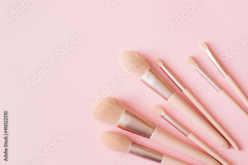 Makeup brushes on pink background. Woman beauty accessory in pastel colors. Flat lay, top view, copy space.