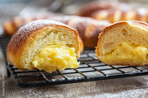 Obraz na plátně Homemade fresh yeast buns with custard filling with powdered sugar on black metal grille