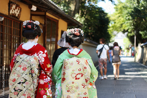 Two geisha in traditional Japanese costumes stroll along Kyoto street 
