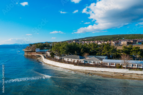 Aerial view of Divnomorskoe small sea resort town on Black Sea coast, beautiful seascape in sunny day.