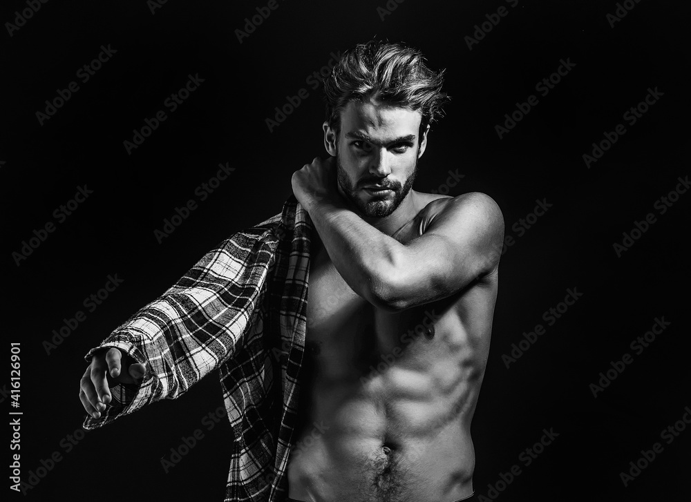 Sexy young handsome naked man with messy hair, wears plaid shirt on dark background. Seductive gay.