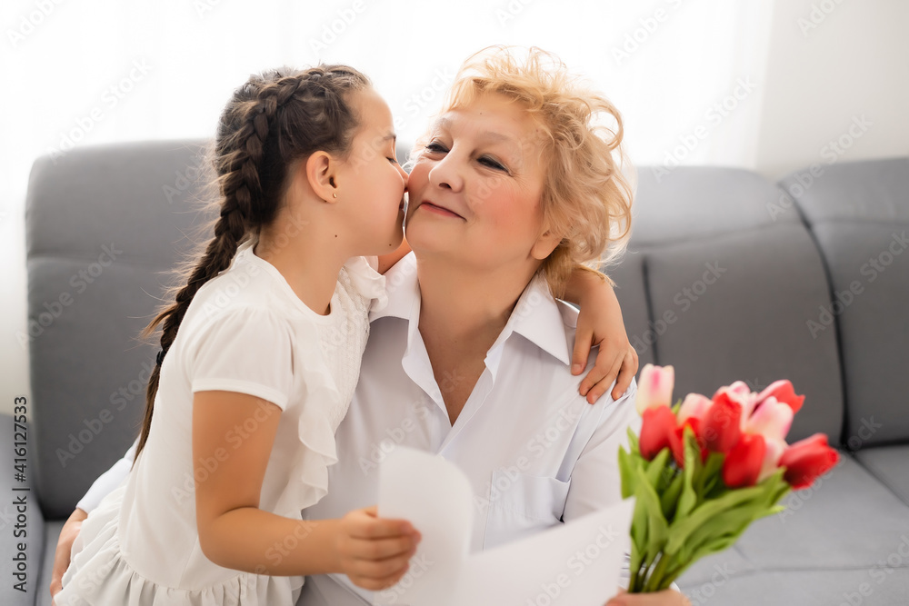 Nice little girl presenting bouquet to her grandmother in light room Nice little girl presenting bouquet to her grandmother in light room