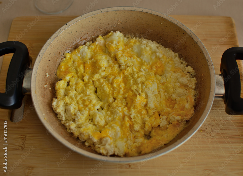 scrambled egg with feta cheese, served with a small frying pan. scrambled egg with feta cheese, served with a small frying pan.