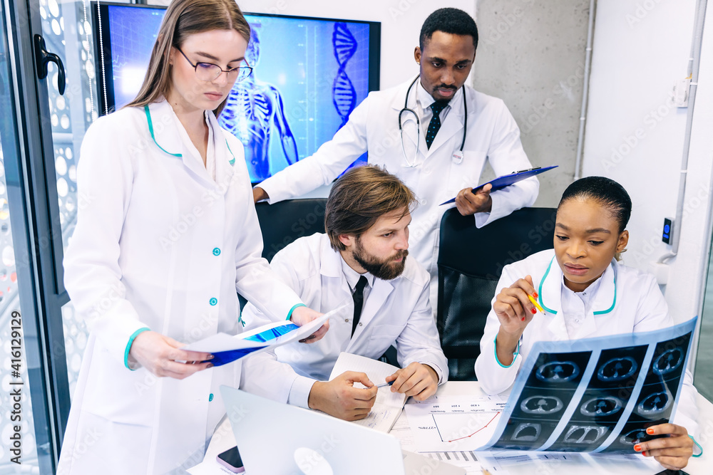 A team of doctors sits at a table and discusses X-rays together A team of doctors sits at a table and discusses X-rays together