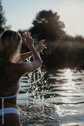 A girl swims in the river at sunset. Splashes of water. 