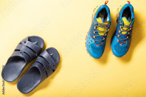 Bath slippers and sports sneakers. Pool slippers and running shoes. Yellow background.