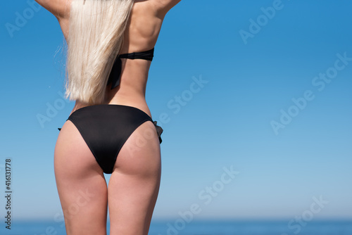 sports buttocks and thighs close-up on the background of the sea. A slender woman athlete goes in for sports on the beach.